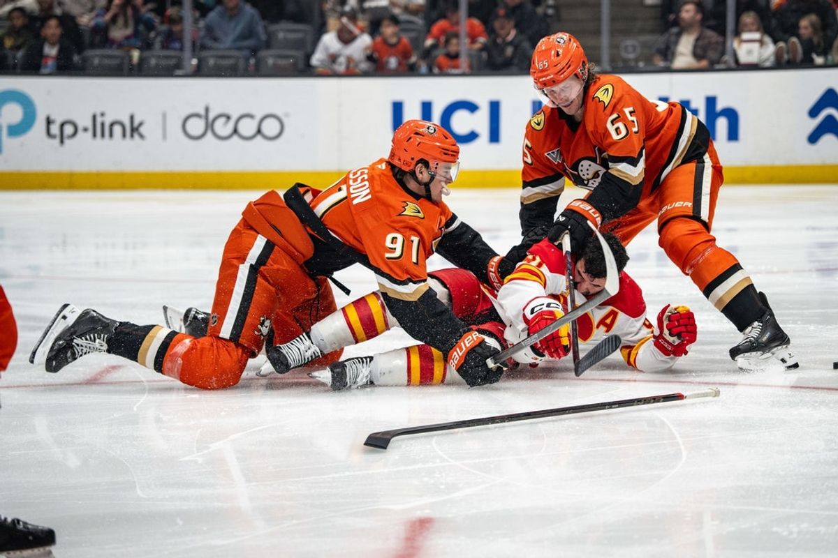 Mar 1, 2026; Anaheim, California, USA; Anaheim Ducks center Leo Carlsson (91) and Anaheim Ducks defenseman Jacob Trouba (65) with Calgary Flames center Nazem Kadri (91) during the third period at Honda Center. Mandatory Credit: Corinne Votaw-Imagn Images