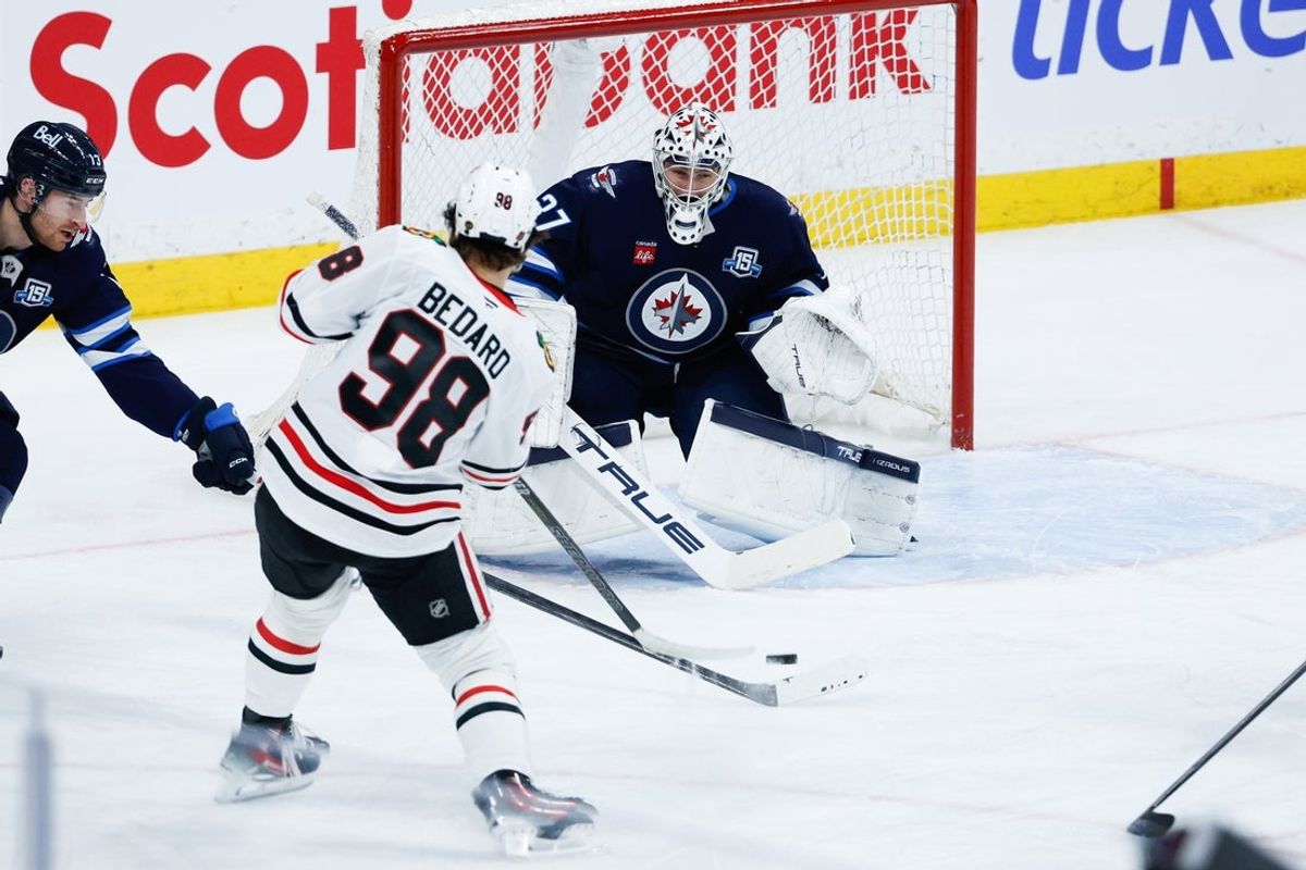 Mar 3, 2026; Winnipeg, Manitoba, CAN;  Winnipeg Jets goalie Connor Hellebuyck (37) makes a save against Chicago Blackhawks forward Connor Bedard (98) during the second period at Canada Life Centre. Mandatory Credit: Terrence Lee-Imagn Images