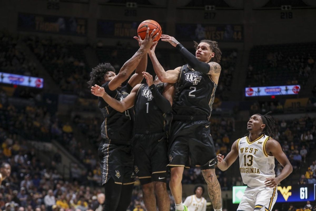 Mar 6, 2026; Morgantown, West Virginia, USA; UCF Knights forward Jamichael Stillwell (4), UCF Knights guard Themus Fulks (1) and UCF Knights guard Riley Kugel (2) jump for a rebound during the second half against the West Virginia Mountaineers at Hope Coliseum. Mandatory Credit: Ben Queen-Imagn Images