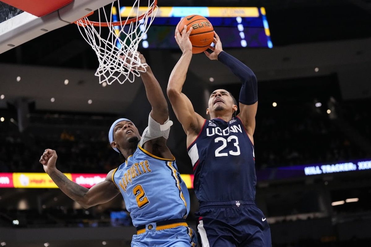 Mar 7, 2026; Milwaukee, Wisconsin, USA;  Connecticut Huskies forward Jayden Ross (23) shoots against Marquette Golden Eagles guard Chase Ross (2) during the first half at Fiserv Forum. Mandatory Credit: Jeff Hanisch-Imagn Images
