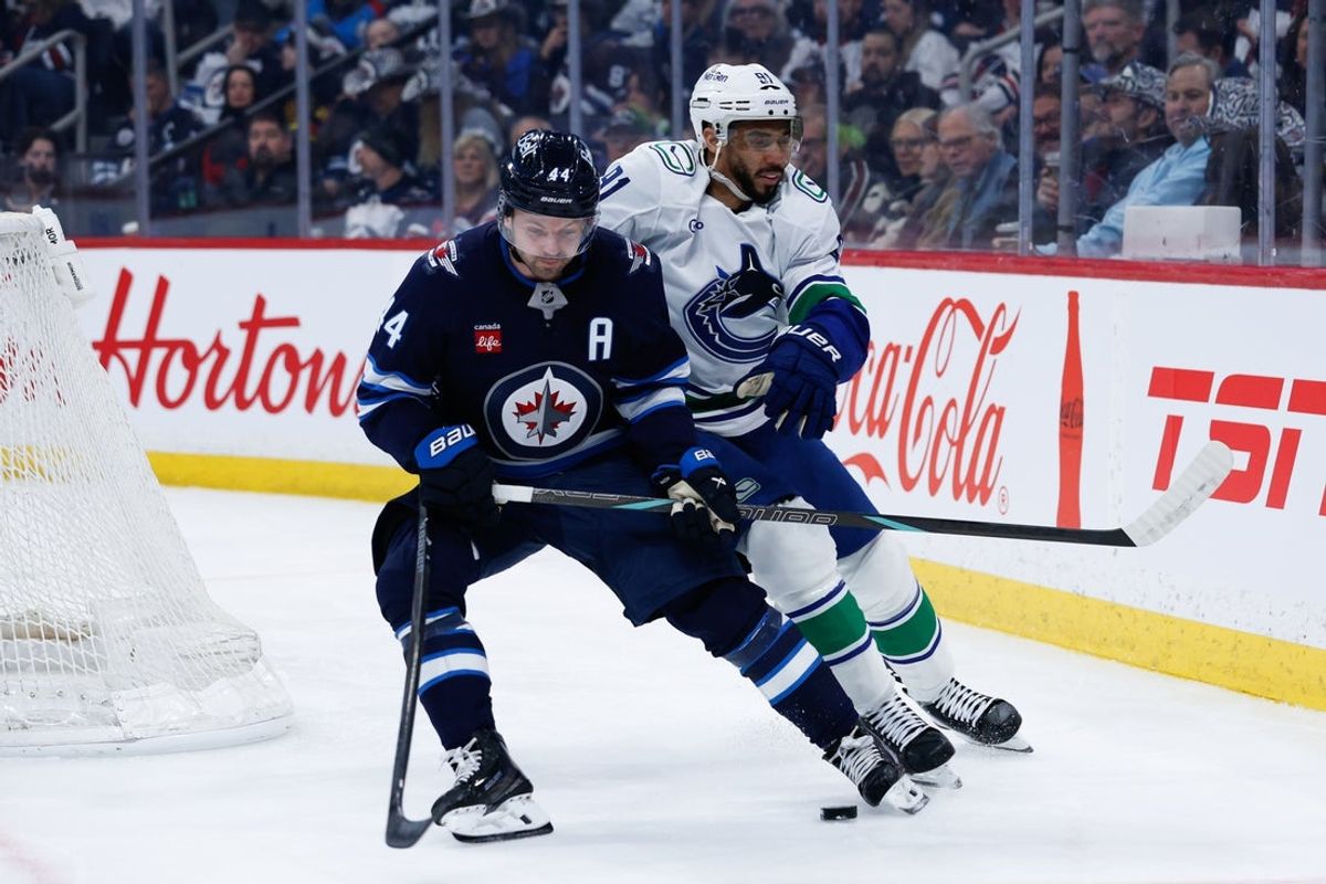 Mar 7, 2026; Winnipeg, Manitoba, CAN;  Winnipeg Jets defenseman Josh Morrissey (44) tries to skate away from Vancouver Canucks forward Evander Kane (91) during the first period at Canada Life Centre. Mandatory Credit: Terrence Lee-Imagn Images