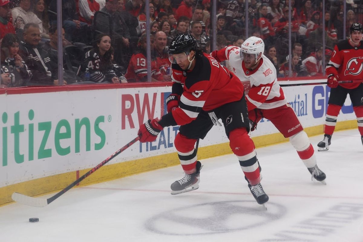 Mar 8, 2026; Newark, New Jersey, USA;  New Jersey Devils defenseman Brenden Dillon (5) moves the puck while Detroit Red Wings center Andrew Copp (18) approaches during the first period at Prudential Center. Mandatory Credit: Thomas Salus-Imagn Images