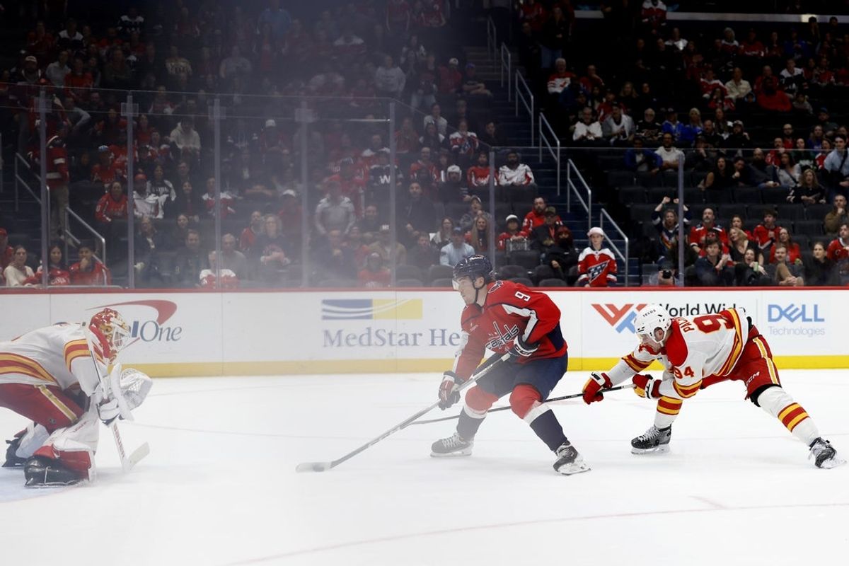 Mar 9, 2026; Washington, District of Columbia, USA; Washington Capitals right wing Ryan Leonard (9) scores a goal on Calgary Flames goaltender Devin Cooley (1) as Flames defenseman Brayden Pachal (94) defends during the third period at Capital One Arena. Mandatory Credit: Geoff Burke-Imagn Images