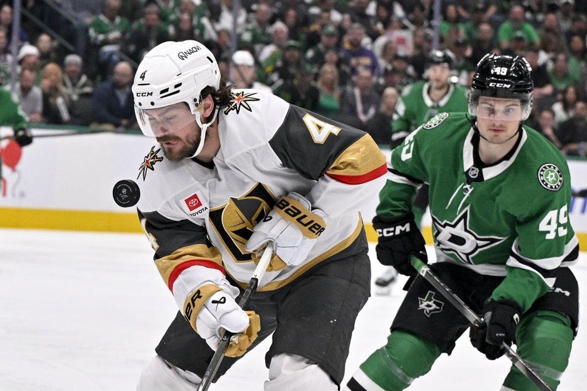 Mar 10, 2026; Dallas, Texas, USA; Vegas Golden Knights defenseman Rasmus Andersson (4) tracks the puck in the air and Dallas Stars center Justin Hryckowian (49) chases during the third period at the American Airlines Center. Mandatory Credit: Jerome Miron-Imagn Images
