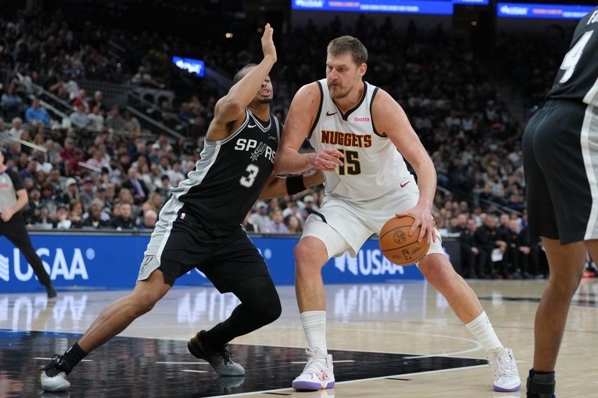 Mar 12, 2026; San Antonio, Texas, USA;  Denver Nuggets center Nikola Jokic (15) dribbles against San Antonio Spurs forward Keldon Johnson (3) in the first half at Frost Bank Center. Mandatory Credit: Daniel Dunn-Imagn Images