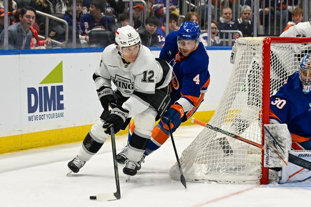 Mar 13, 2026; Elmont, New York, USA; Los Angeles Kings left wing Trevor Moore (12) skates the puck from behind the net defended by New York Islanders defenseman Carson Soucy (4) during the third period at UBS Arena. Mandatory Credit: Dennis Schneidler-Imagn Images