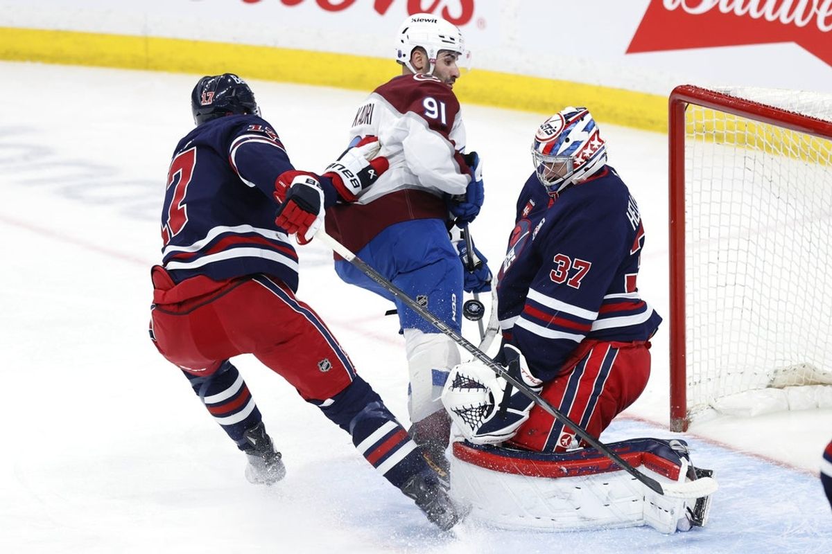 Mar 14, 2026; Winnipeg, Manitoba, CAN; Winnipeg Jets center Adam Lowry (17) checks Colorado Avalanche center Nazem Kadri (91) in front of Winnipeg Jets goaltender Connor Hellebuyck (37) in the first period at Canada Life Centre. Mandatory Credit: James Carey Lauder-Imagn Images