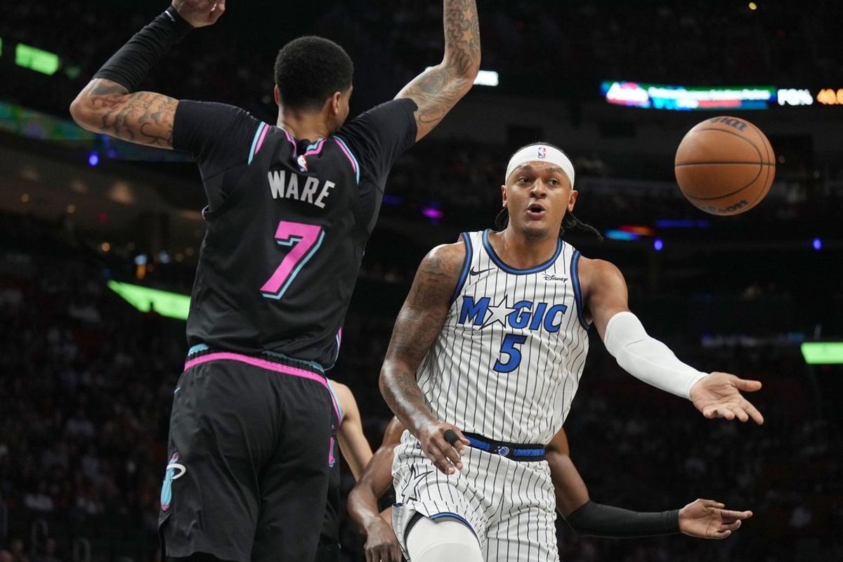 Mar 14, 2026; Miami, Florida, USA;  Orlando Magic forward Paolo Banchero (5) passes the ball as he drives to the basket as Miami Heat center Kel'el Ware (7) defends during the first half at Kaseya Center. Mandatory Credit: Jim Rassol-Imagn Images