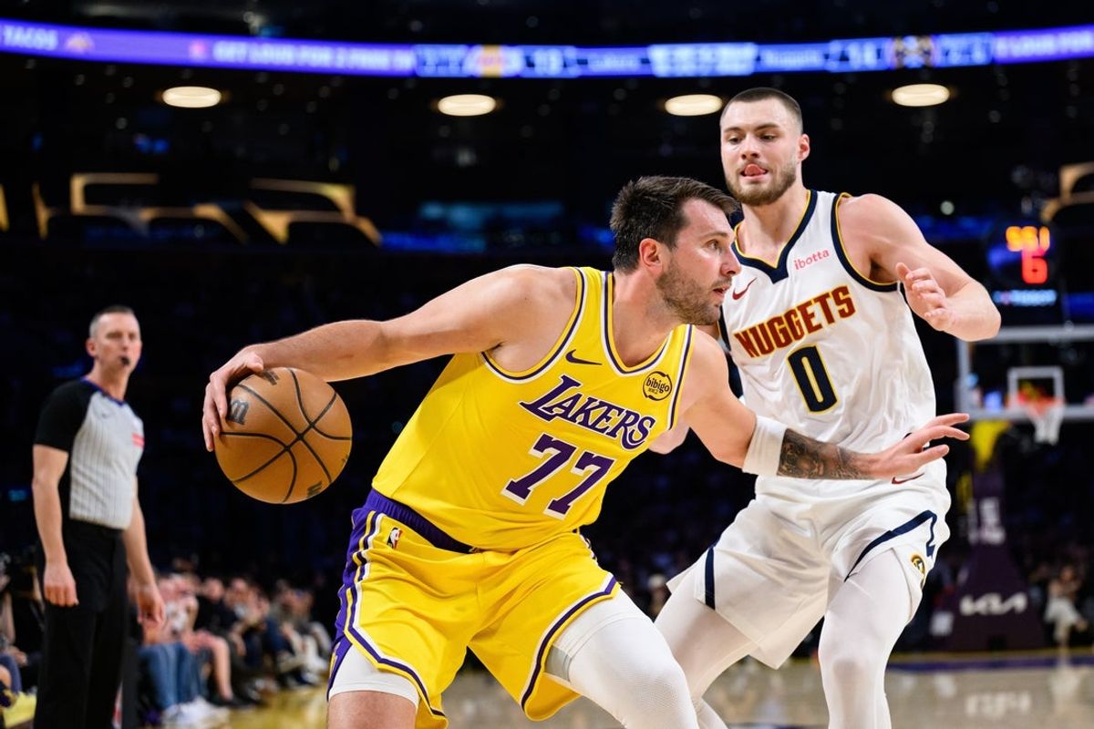 Mar 14, 2026; Los Angeles, California, USA; Los Angeles Lakers guard Luka Doncic (77) controls the ball while under pressure from Denver Nuggets guard Christian Braun (0) during the first half at Crypto.com Arena. Mandatory Credit: William Liang-Imagn Images