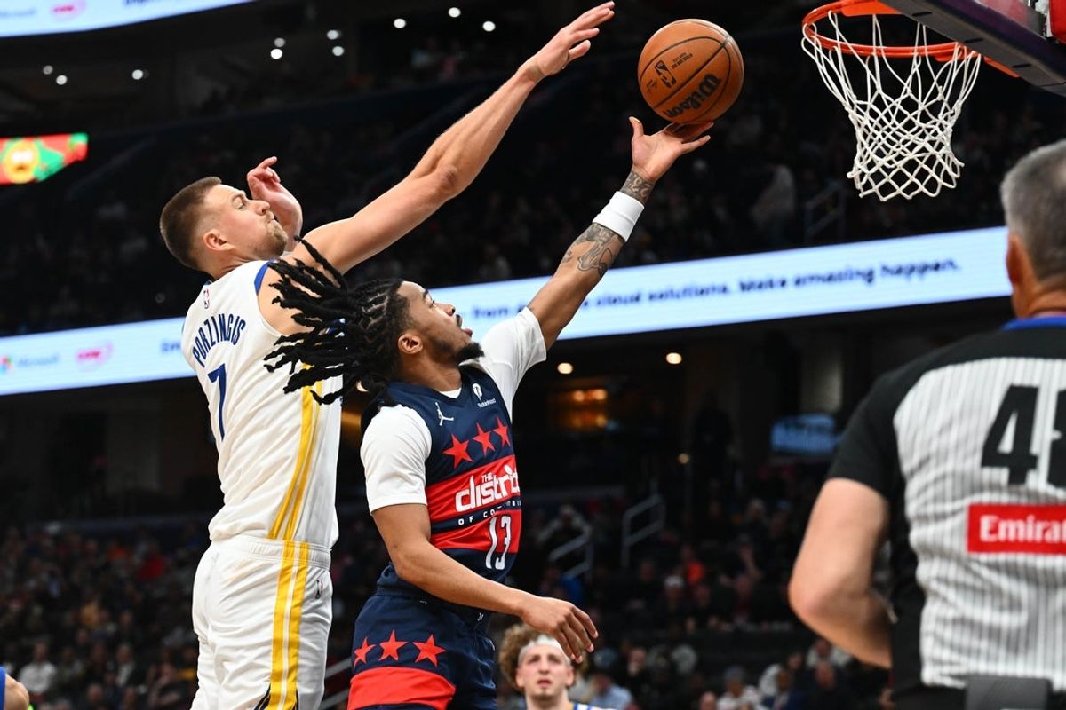 Mar 16, 2026; Washington, District of Columbia, USA; Washington Wizards guard Sharife Cooper (13) has shot blocked by Golden State Warriors center Kristaps Porzingis (7) during the first half at Capital One Arena. Mandatory Credit: Brad Mills-Imagn Images