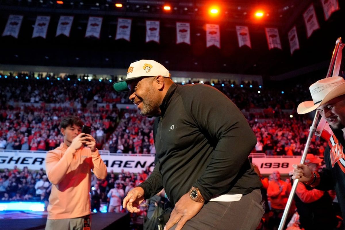 Former Oklahoma State wrestler Daniel Cormier leads the Cowboys out before a college wrestling dual between the Oklahoma State University Cowboys (OSU) and the Iowa Hawkeyes at Gallagher-Iba Arena in Stillwater, Okla., Sunday, Feb. 22, 2026.