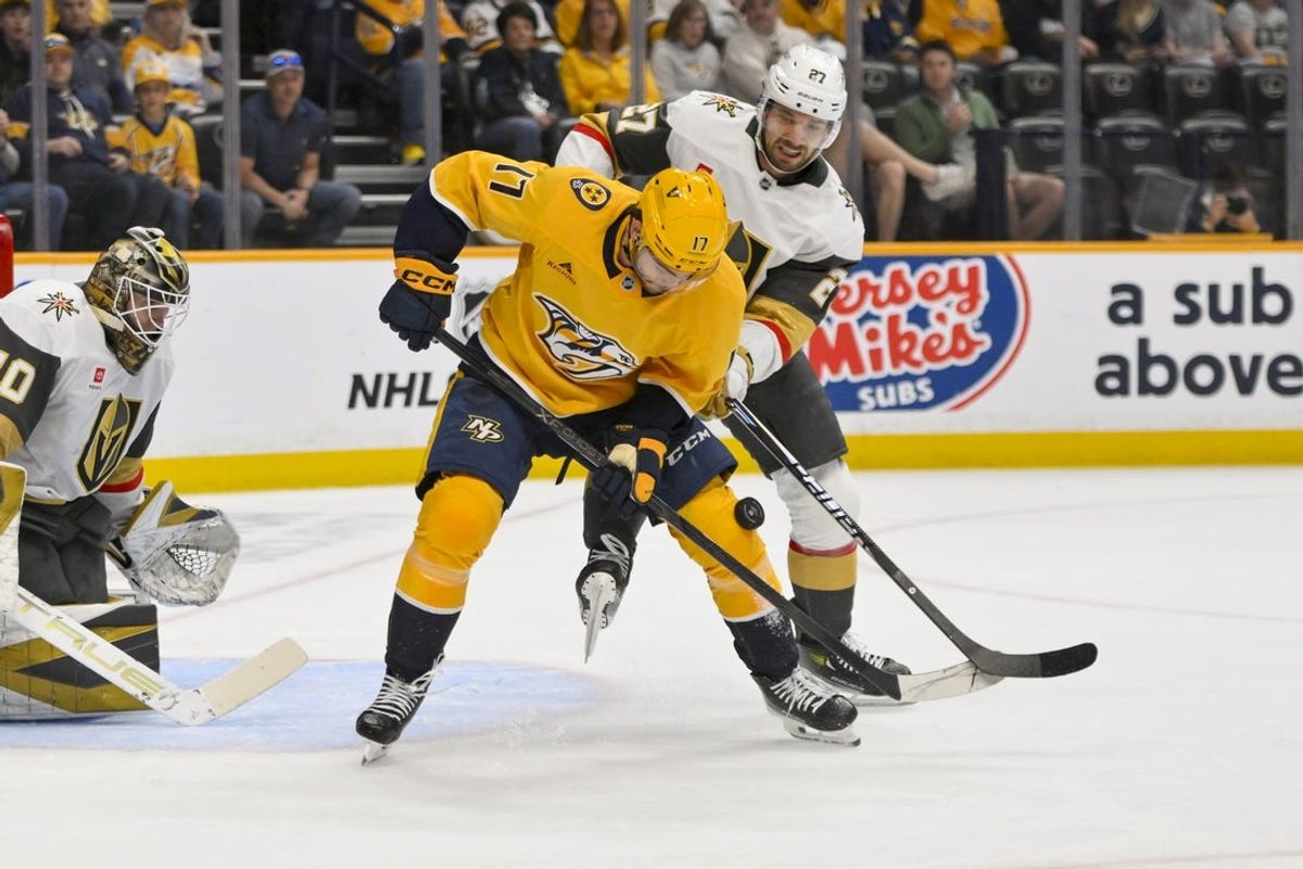 Mar 21, 2026; Nashville, Tennessee, USA;  Nashville Predators center Tyson Jost (17) and Vegas Golden Knights center Brett Howden (21) battle for the puck during the first period at Bridgestone Arena. Mandatory Credit: Steve Roberts-Imagn Images