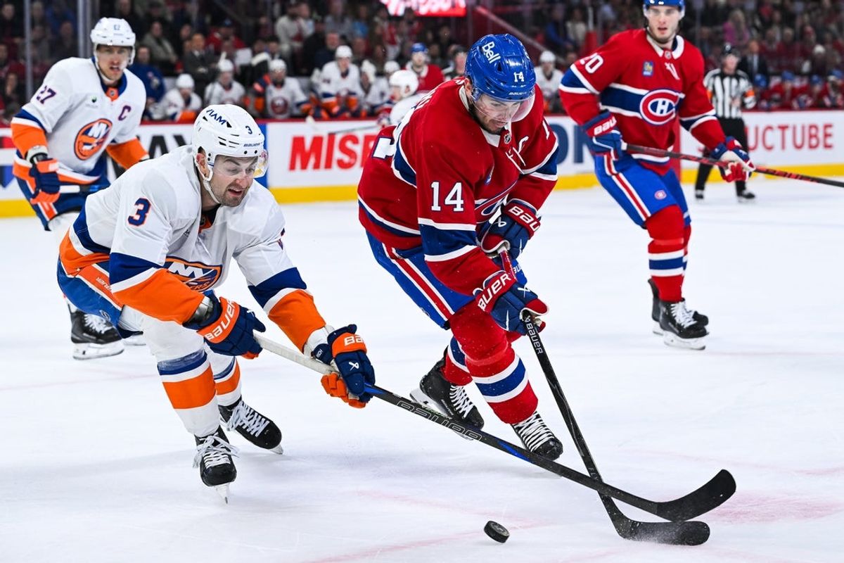 Mar 21, 2026; Montreal, Quebec, CAN; Montreal Canadiens center Nick Suzuki (14) plays the puck against New York Islanders defenseman Adam Pelech (3) during the first period at Bell Centre. Mandatory Credit: David Kirouac-Imagn Images