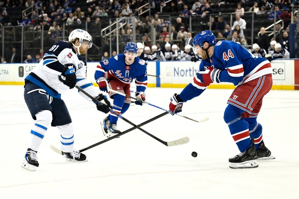 Mar 22, 2026; New York, New York, USA; Winnipeg Jets left wing Kyle Connor (81) passes the puck while defended by New York Rangers defenseman Vladislav Gavrikov (44) during the first period at Madison Square Garden. Mandatory Credit: John Jones-Imagn Images