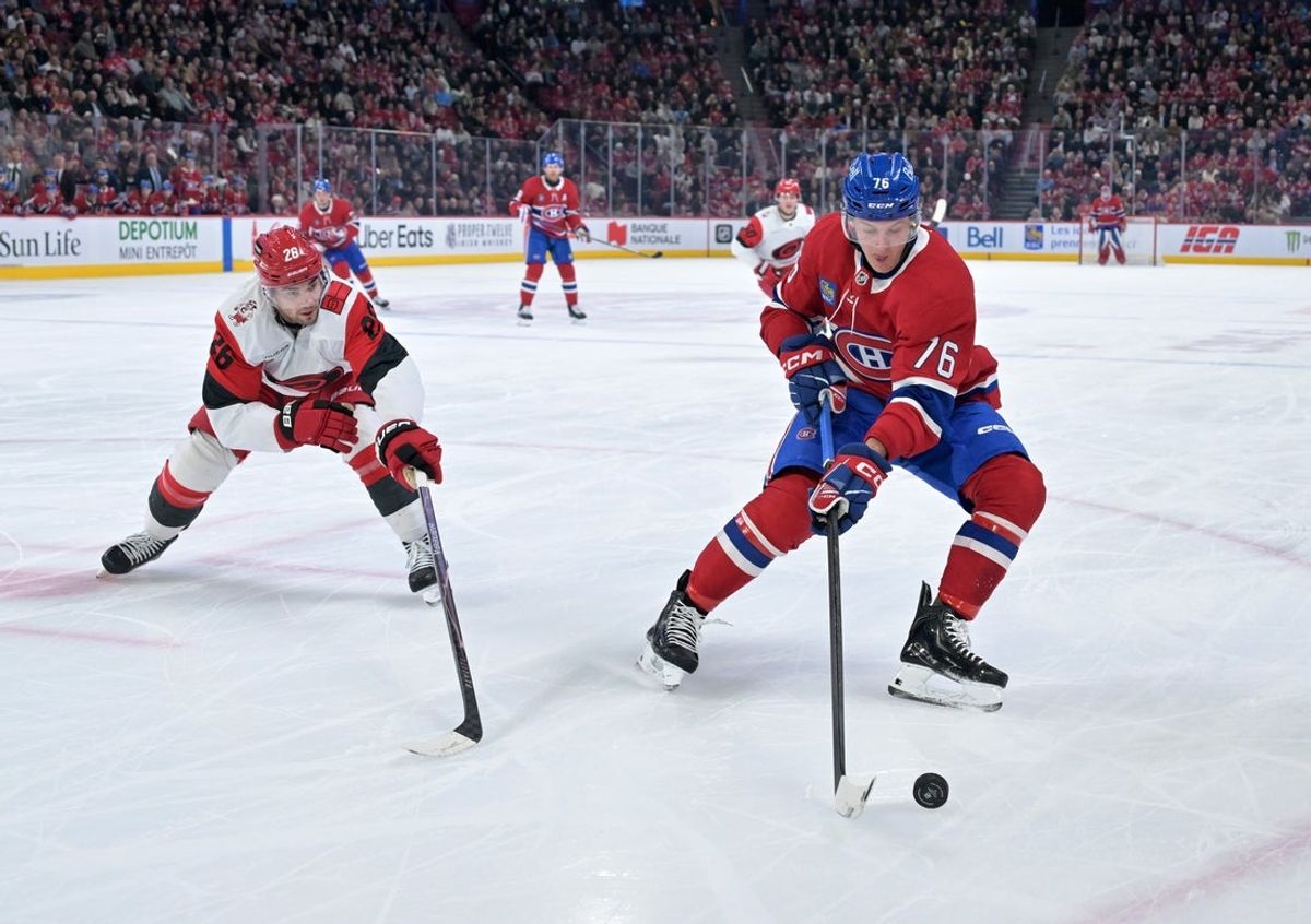 Mar 24, 2026; Montreal, Quebec, CAN; Montreal Canadiens forward Zack Bolduc (76) plays the puck and Carolina Hurricanes defenseman Sean Walker (26) defends during the first period at the Bell Centre. Mandatory Credit: Eric Bolte-Imagn Images