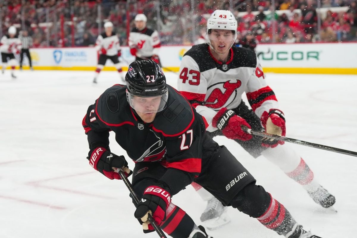 Mar 28, 2026; Raleigh, North Carolina, USA;  Carolina Hurricanes left wing Nikolaj Ehlers (27) and New Jersey Devils defenseman Luke Hughes (43) follow the puck during the third period at Lenovo Center. Mandatory Credit: James Guillory-Imagn Images