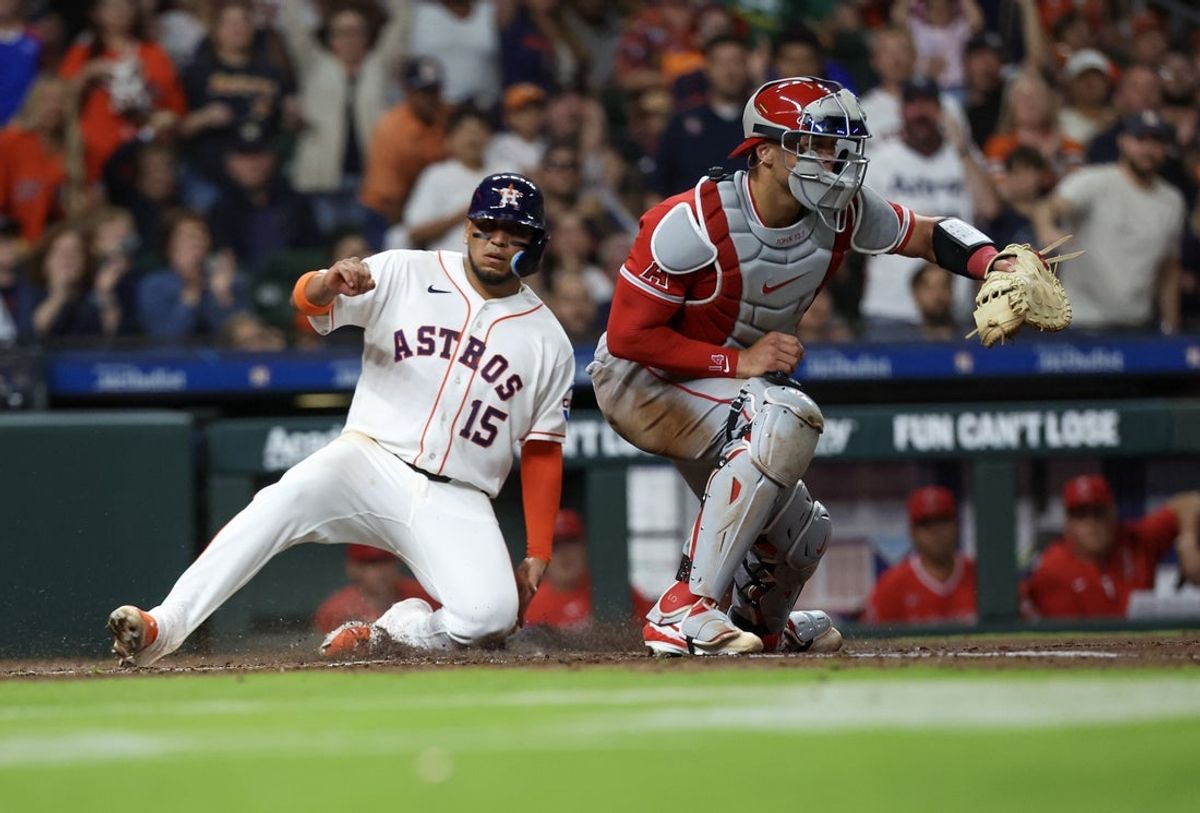 Mar 28, 2026; Houston, Texas, USA; Houston Astros third baseman Isaac Paredes (15) slides at home safely against Los Angeles Angels catcher Logan O'Hoppe (14) in the fifth inning at Daikin Park. Mandatory Credit: Thomas Shea-Imagn Images