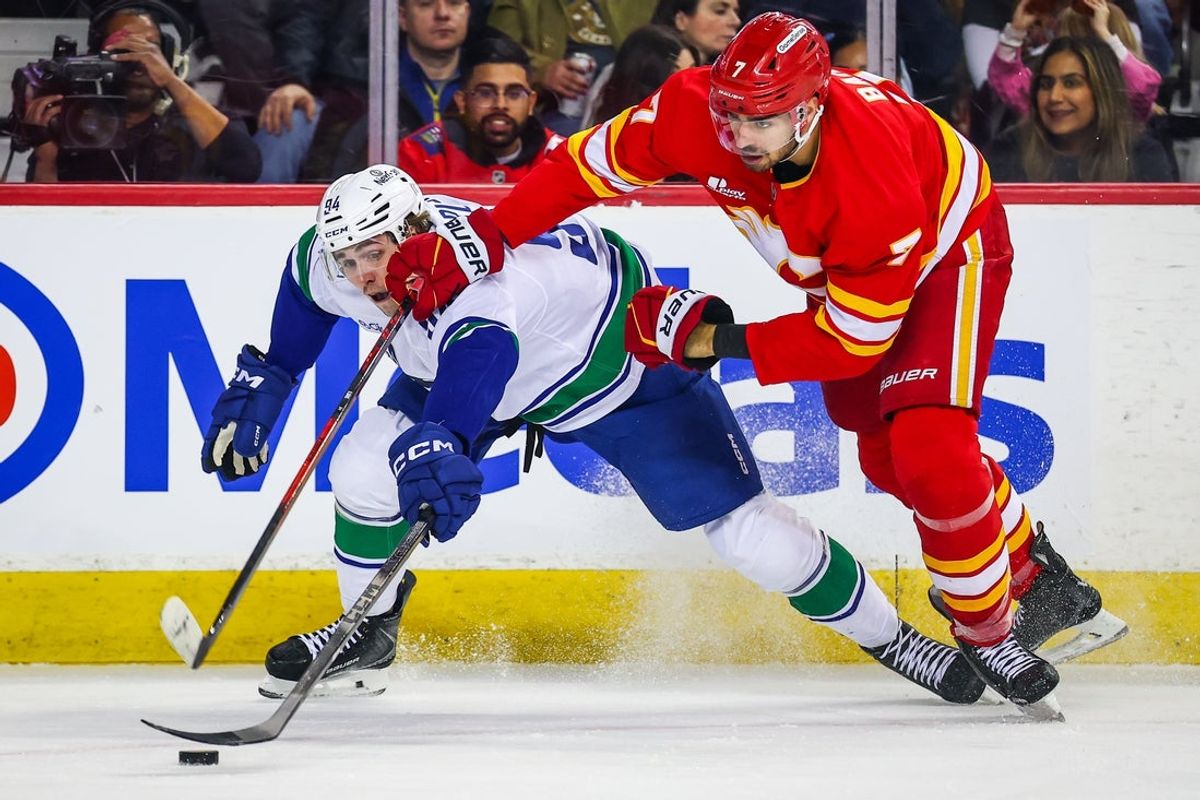 Mar 28, 2026; Calgary, Alberta, CAN; Vancouver Canucks center Linus Karlsson (94) and Calgary Flames defenseman Kevin Bahl (7) battle for the puck during the first period at Scotiabank Saddledome. Mandatory Credit: Sergei Belski-Imagn Images