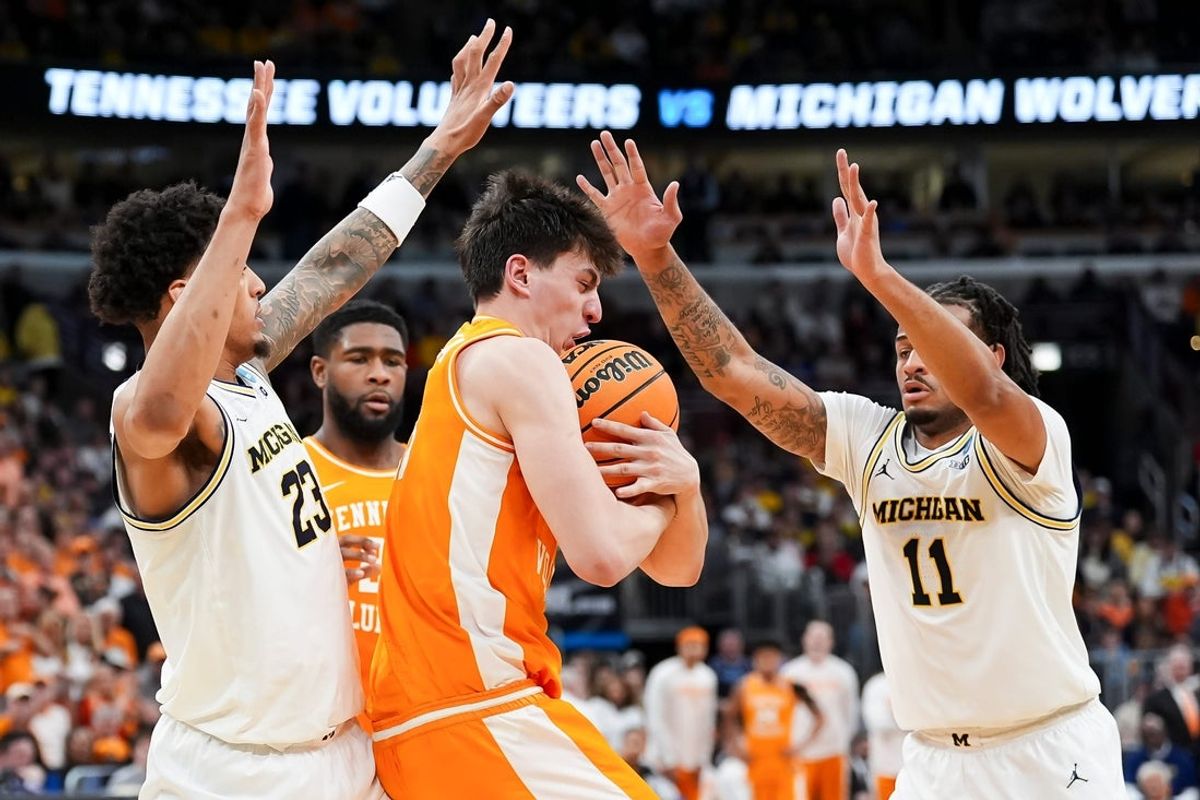 Tennessee forward J.P. Estrella (13) holds onto the rebound while defended by Michigan forward Yaxel Lendeborg (23) and Michigan guard Roddy Gayle Jr. (11) during a NCAA Tournament Elite 8 game between Tennessee and Michigan at the United Center in Chicago on March 29, 2026.
