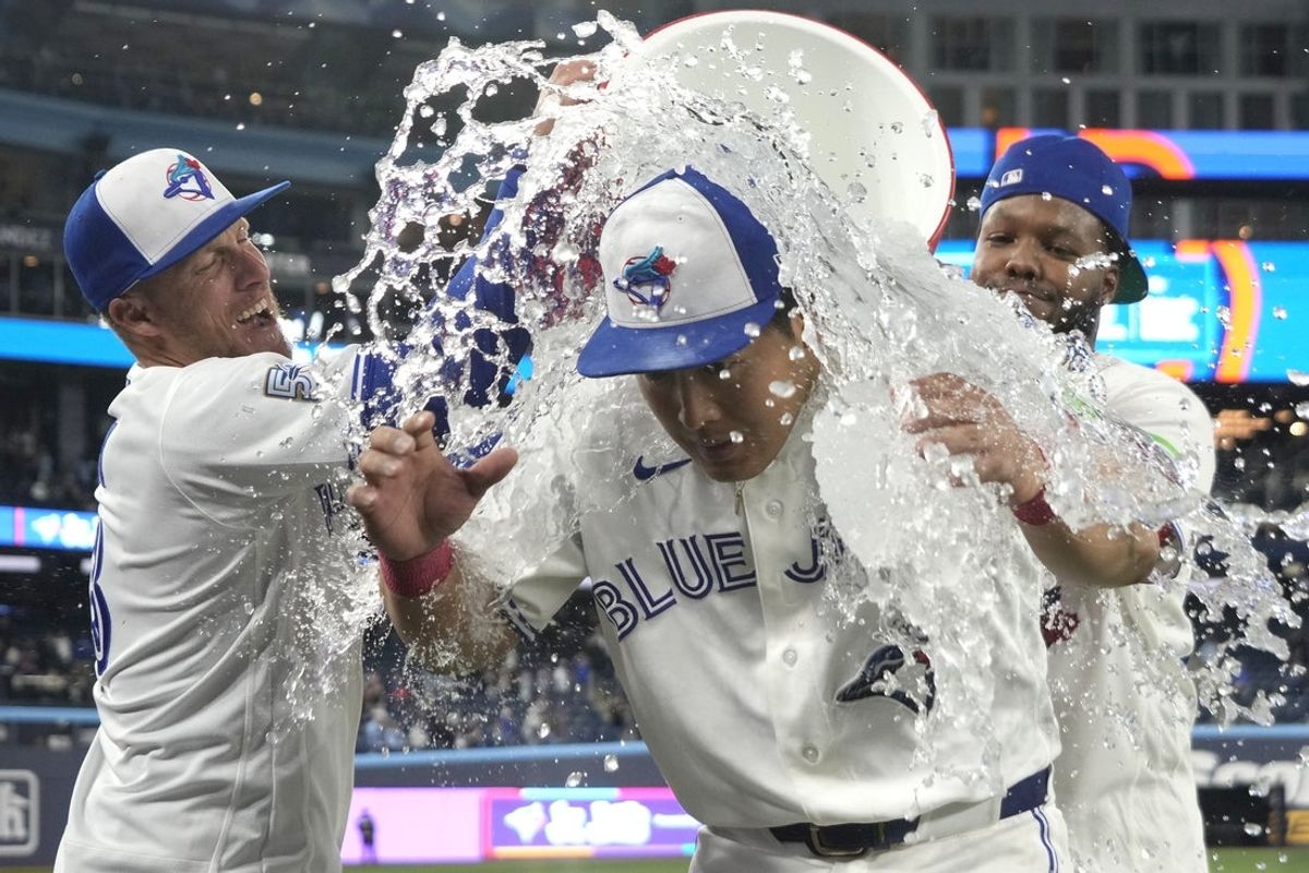 Mar 29, 2026; Toronto, Ontario, CAN; Toronto Blue Jays third baseman Kazuma Okamoto (center) reacts as he gets doused with ice water by oufielder Myles Straw (left) and first baseman Vladimir Guerrero Jr. (right) after a win over the Athletics at Rogers Centre. Mandatory Credit: John E. Sokolowski-Imagn Images