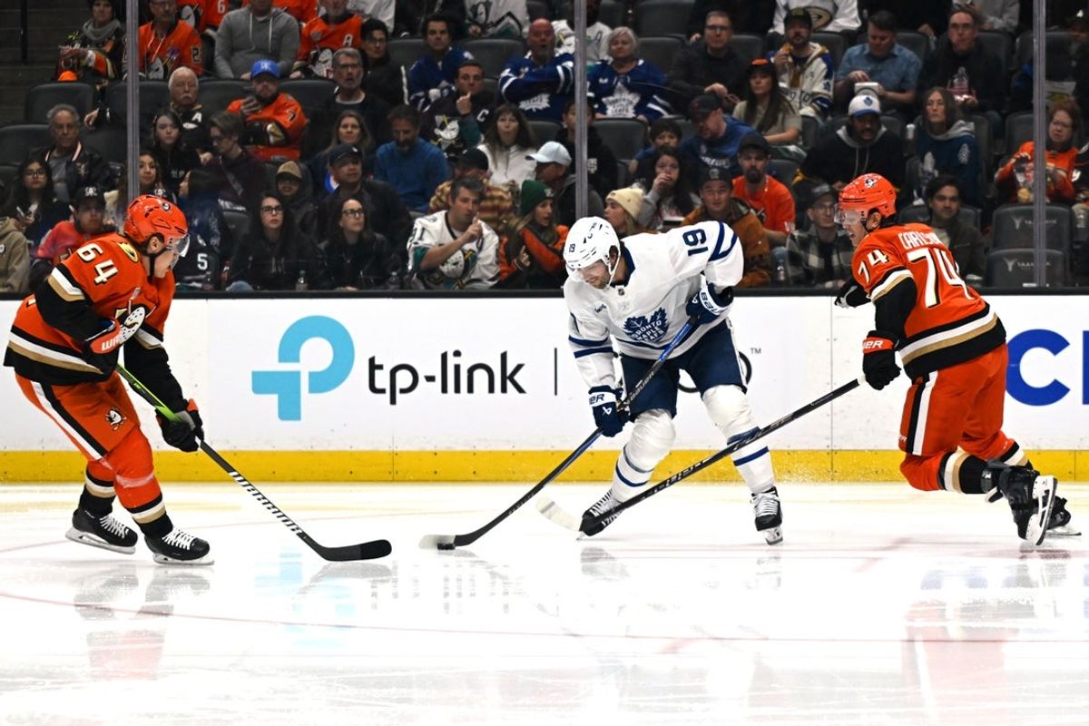 Mar 30, 2026; Anaheim, California, USA; Toronto Maple Leafs center Calle Jarnkrok (19) battles for the puck against Anaheim Ducks defenseman John Carlson (74) and center Mikael Granlund (64) during the first period at Honda Center. Mandatory Credit: Griffin Hooper-Imagn Images