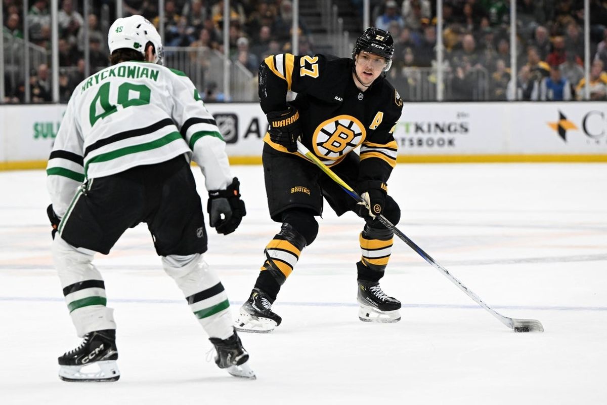 Mar 31, 2026; Boston, Massachusetts, USA; Boston Bruins defenseman Hampus Lindholm (27) controls the puck against Dallas Stars center Justin Hryckowian (49) during the first period at the TD Garden. Mandatory Credit: Brian Fluharty-Imagn Images