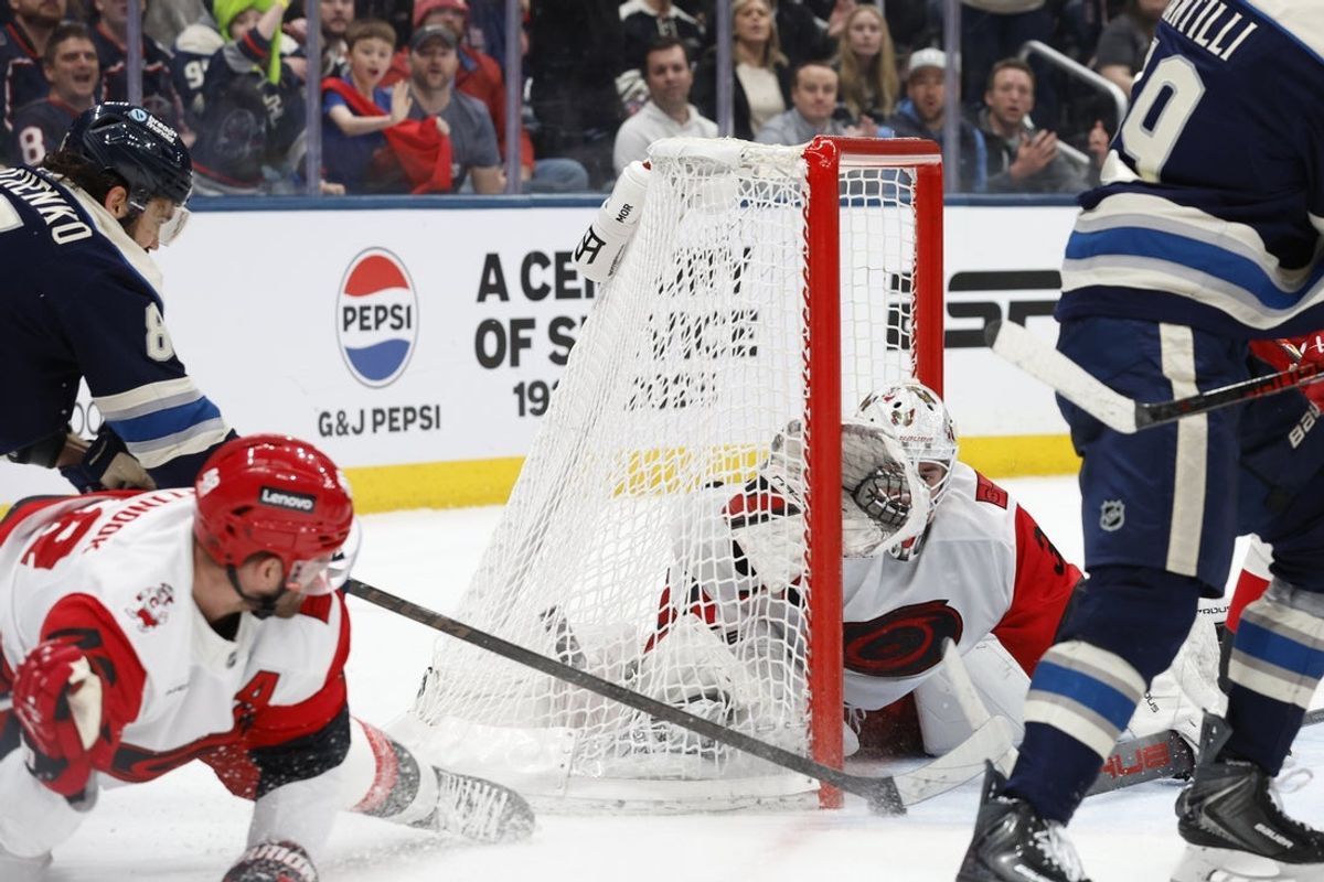 Mar 31, 2026; Columbus, Ohio, USA; Columbus Blue Jackets right wing Kirill Marchenko (86) slides the puck under Carolina Hurricanes goalie Brandon Bussi (32) for a goal during the second period at Nationwide Arena. Mandatory Credit: Russell LaBounty-Imagn Images