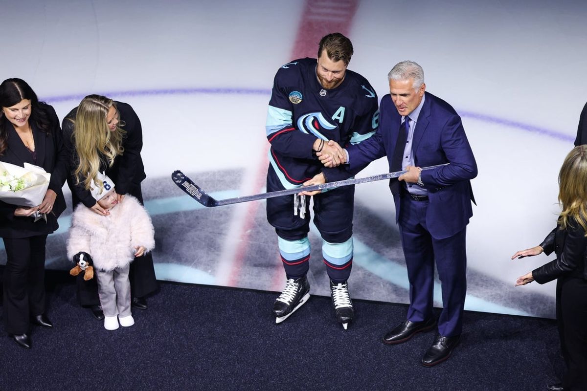 Apr 2, 2026; Seattle, Washington, USA; Seattle Kraken defenseman Adam Larsson (6) shakes hands with general manager Ron Francis for his 1000th game presentation before the match against the Utah Mammoth at Climate Pledge Arena. Mandatory Credit: Kevin Ng-Imagn Images