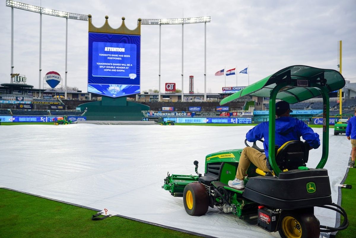 Apr 3, 2026; Kansas City, Missouri, USA; A general view as a grounds crew employee anchors down the tarp as the game between the Kansas City Royals and Milwaukee Brewers is postponed and will be played as part of a double-header on Saturday April 4th at Kauffman Stadium. Mandatory Credit: Denny Medley-Imagn Images