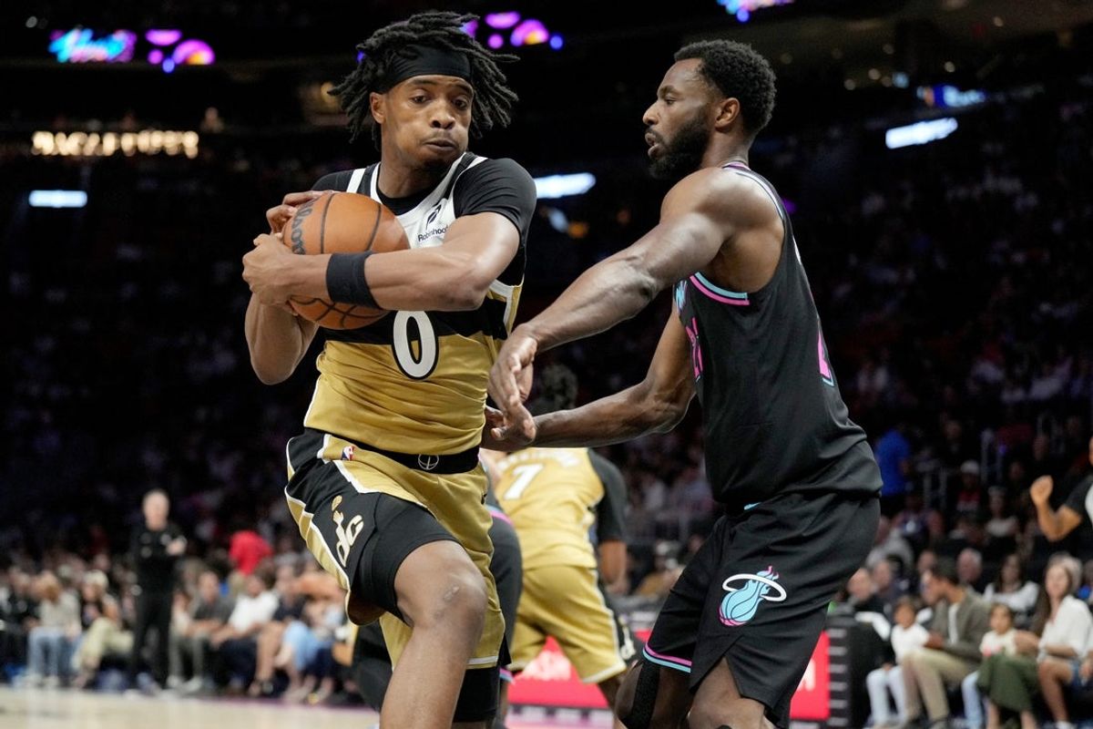 Apr 4, 2026; Miami, Florida, USA;  Washington Wizards guard Bilal Coulibaly (0) takes a rebound away from Miami Heat forward Andrew Wiggins (22) during the first half at Kaseya Center. Mandatory Credit: Jim Rassol-Imagn Images