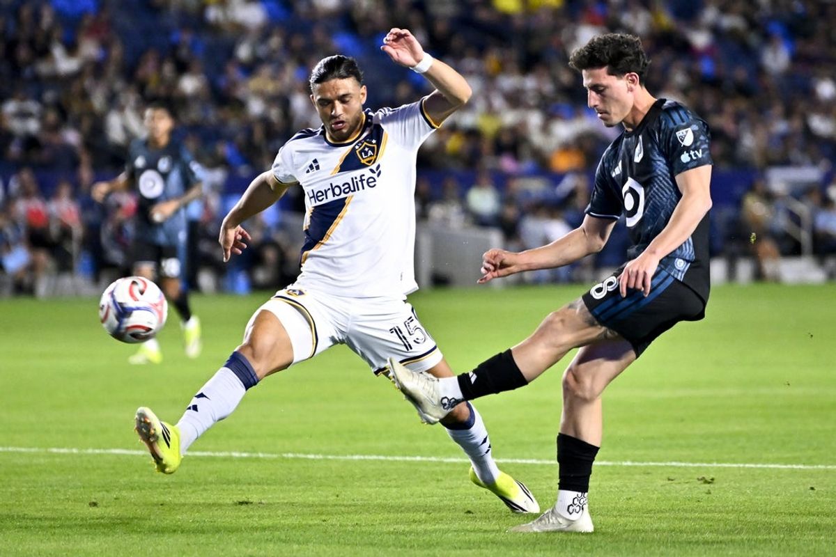 Apr 4, 2026; Carson, California, USA; Minnesota United forward Tomás Chancalay (8) crosses the ball while LA Galaxy midfielder Justin Haak (15) defends during the first half at Dignity Health Sports Park. Mandatory Credit: Kelvin Kuo-Imagn Images