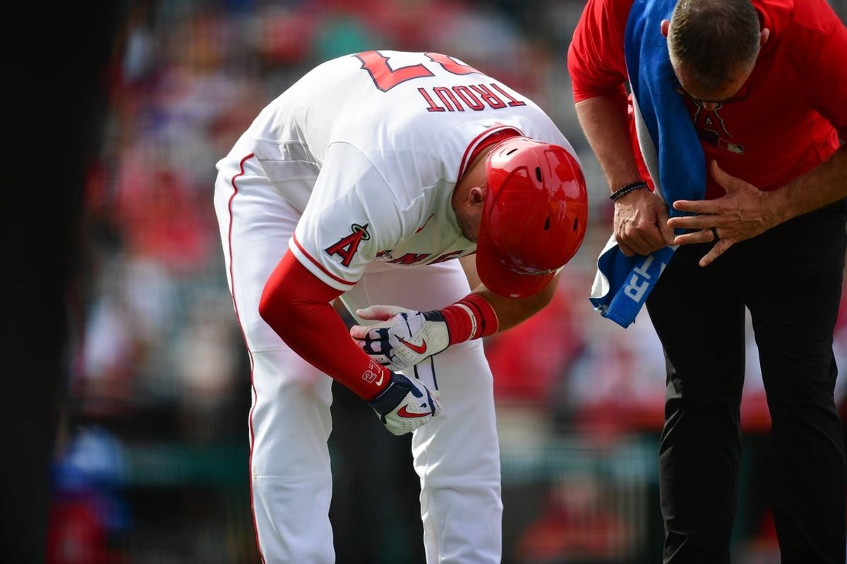 Apr 5, 2026; Anaheim, California, USA; Los Angeles Angels center fielder Mike Trout (27) has his hand checked by trainer Mike Frostad after being hit by pitch from Seattle Mariners pitcher Casey Legumina (64) during the eighth inning at Angel Stadium. Mandatory Credit: Gary A. Vasquez-Imagn Images