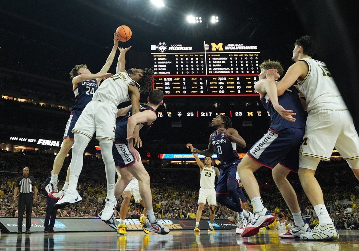 Apr 6, 2026; Indianapolis, IN, USA; Michigan Wolverines forward Morez Johnson Jr. (21) and Connecticut Huskies guard Braylon Mullins (24) in action in the first half during the national championship of the Final Four of the men's 2026 NCAA Tournament at Lucas Oil Stadium. Mandatory Credit: Robert Deutsch-Imagn Images