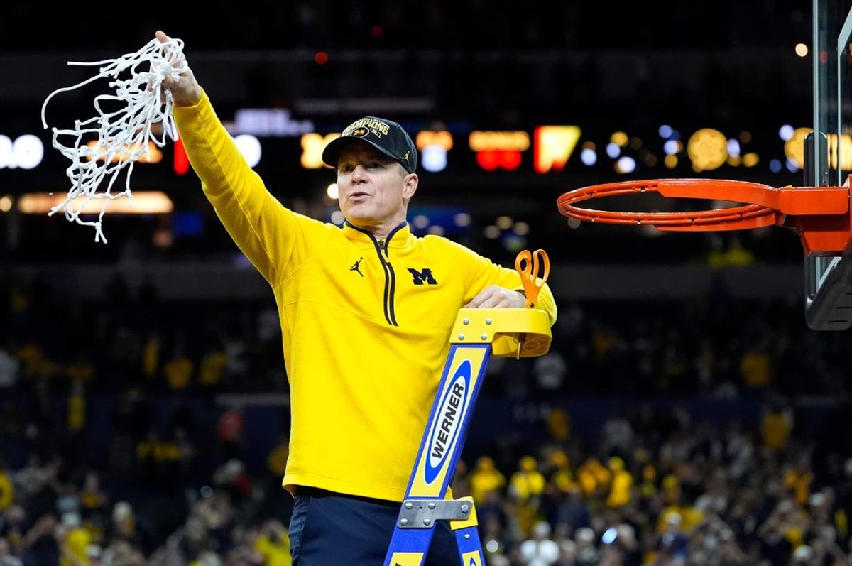 Michigan head coach Dusty May swings the net after winning the NCAA national championship against Connecticut at Lucas Oil Stadium in Indianapolis on Monday, April 6, 2026.