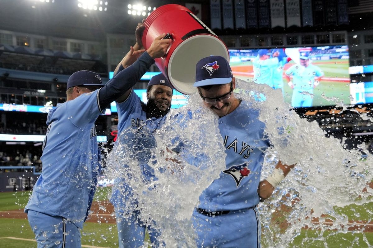 Apr 8, 2026; Toronto, Ontario, CAN; Toronto Blue Jays left fielder Davis Schneider (center) gets doused with ice water by center fielder Myles Straw (3) and first baseman Vladimir Guerrero Jr. (27) after a win over the Los Angeles Dodgers at Rogers Centre. Mandatory Credit: John E. Sokolowski-Imagn Images