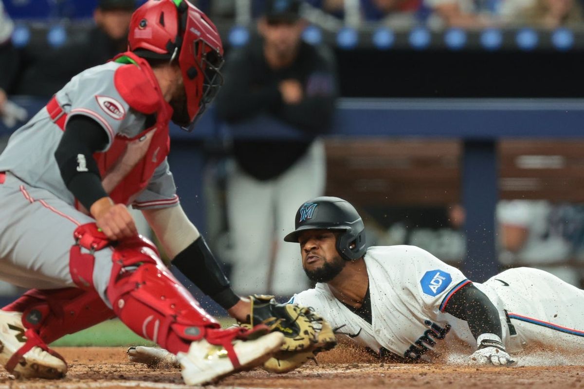 Apr 9, 2026; Miami, Florida, USA; Miami Marlins shortstop Otto Lopez (6) slides at home plate and scores against Cincinnati Reds catcher P.J. Higgins (65) during the fourth inning at loanDepot Park. Mandatory Credit: Sam Navarro-Imagn Images