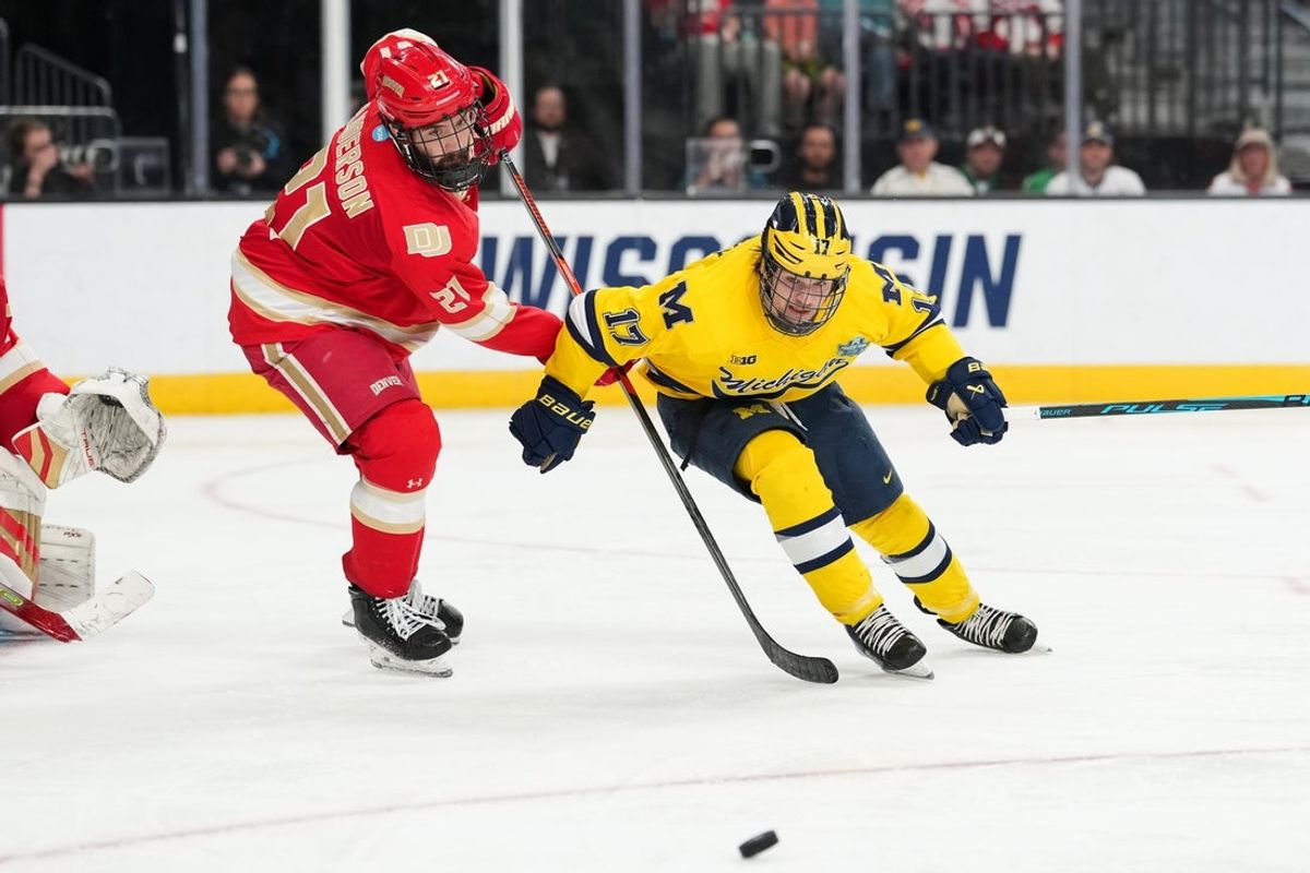 Apr 9, 2026; Las Vegas, Nevada, UNITED STATES; Denver Pioneers defenseman Kent Anderson (21) and Michigan Wolverines forward Garrett Schifsky (17) battle for the puck in the third period in the semifinals of the NCAA men's ice hockey Frozen Four at T-Mobile Arena. Mandatory Credit: Lucas Peltier-Imagn Images
