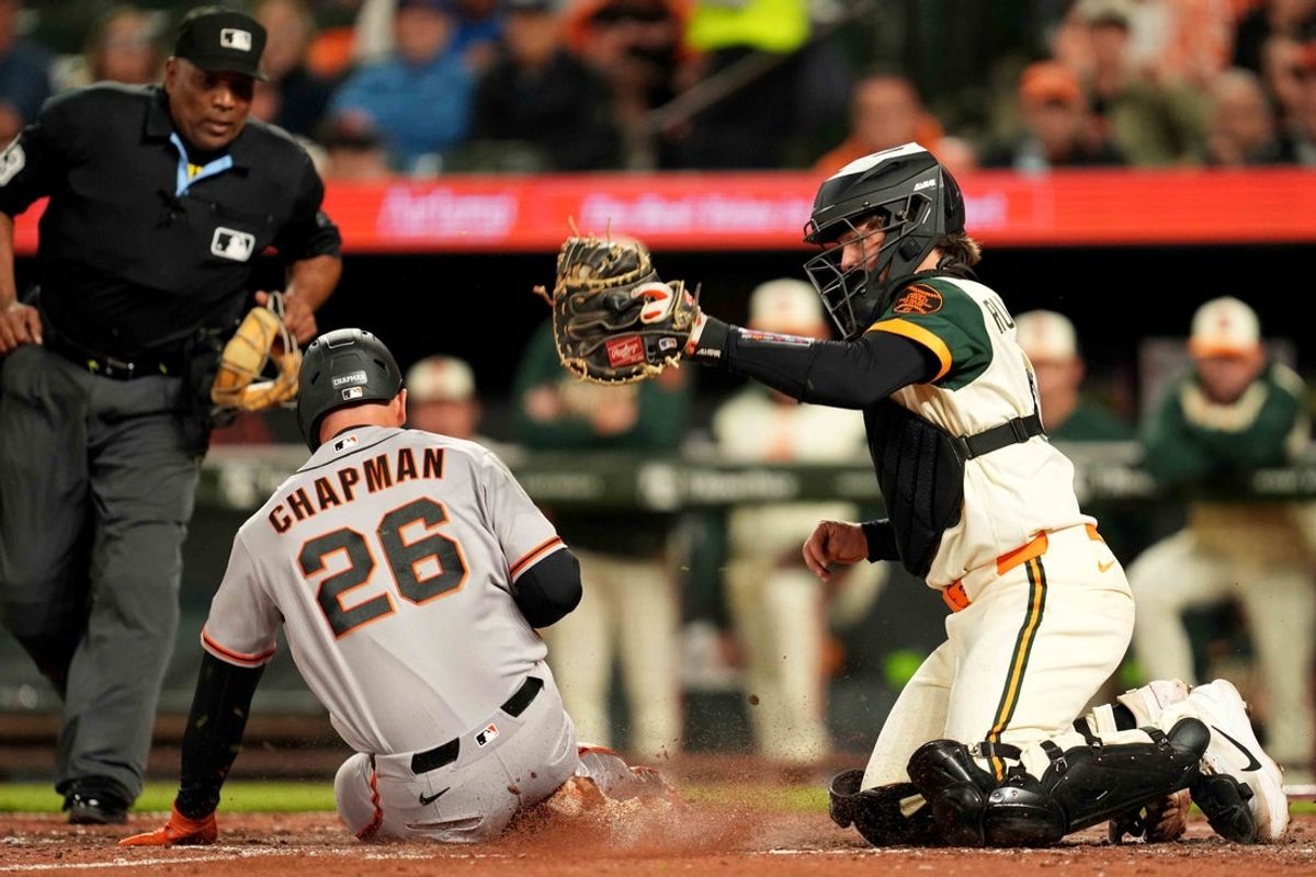 Apr 10, 2026; Baltimore, Maryland, USA; San Francisco Giants third baseman Matt Chapman (26) slides safely to score a run during the seventh inning ahead of a tag attempt by Baltimore Orioles catcher Adley Rutschman (35) at Oriole Park at Camden Yards. Mandatory Credit: Mitch Stringer-Imagn Images