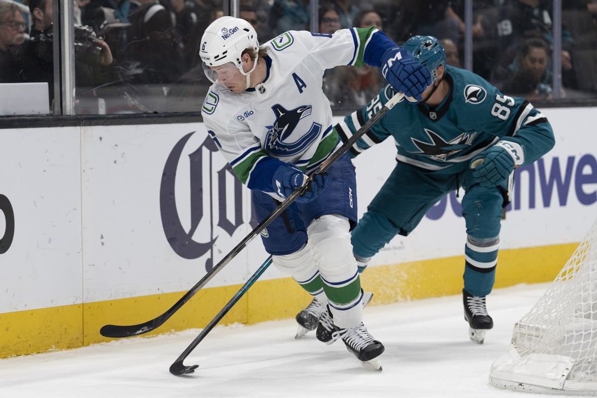 Apr 11, 2026; San Jose, California, USA;  Vancouver Canucks right wing Brock Boeser (6) and San Jose Sharks defenseman Shakir Mukhamadullin (85) battle for control of the puck during the first period at SAP Center at San Jose. Mandatory Credit: Stan Szeto-Imagn Images