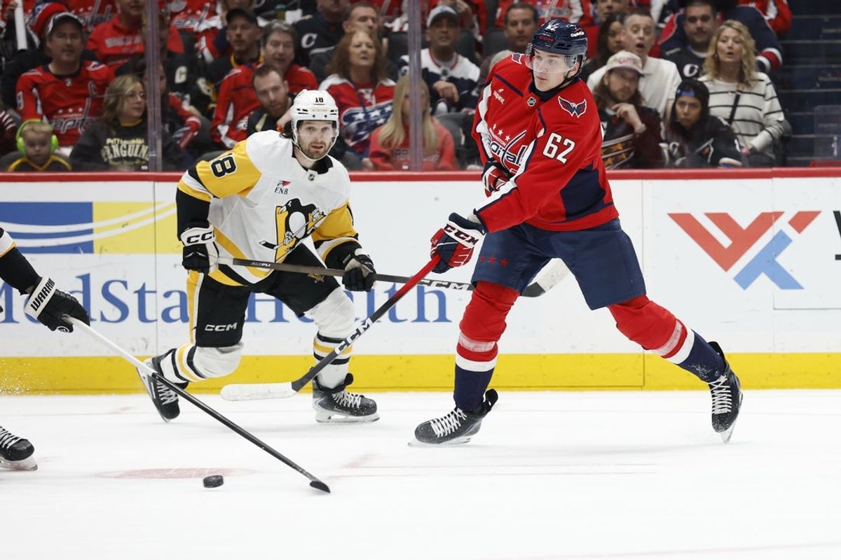 Apr 12, 2026; Washington, District of Columbia, USA; Washington Capitals left wing Ilya Protas (62) shoots the puck as Pittsburgh Penguins center Tommy Novak (18) looks on during the first period at Capital One Arena. Mandatory Credit: Geoff Burke-Imagn Images