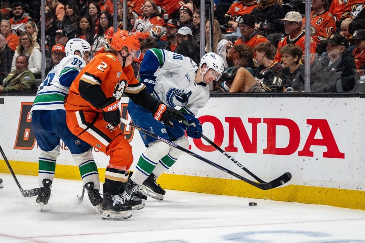 Apr 12, 2026; Anaheim, California, USA; Vancouver Canucks left wing Drew O'Connor (18) skates with the puck against Anaheim Ducks defenseman Jackson LaCombe (2) at Honda Center. Mandatory Credit: Corinne Votaw-Imagn Images