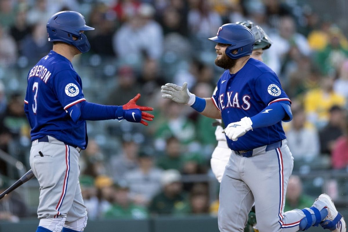 Apr 13, 2026; West Sacramento, California, USA; Texas Rangers first baseman Jake Burger (right) gets a congratulatory handshake from designated hitter Joc Pederson (3) after hitting a solo home run against the Athletics during the third inning at Sutter Health Park. Mandatory Credit: D. Ross Cameron-Imagn Images