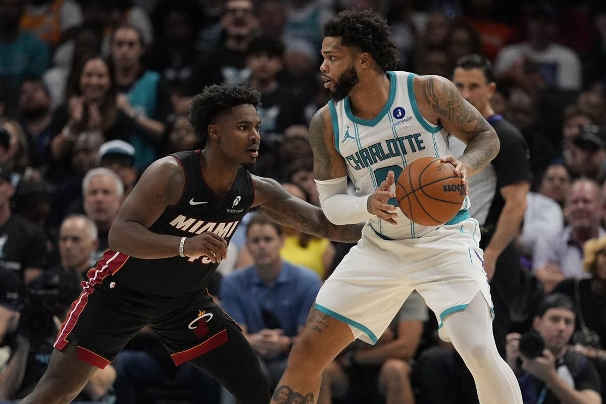 Apr 14, 2026; Charlotte, North Carolina, USA; Charlotte Hornets forward Miles Bridges (0) looks to pass guarded by Miami Heat guard Davion Mitchell (45) during the second quarter during the play-in rounds between the Charlotte Hornets and the Miami Heat of the 2026 NBA Playoffs at Spectrum Center. Mandatory Credit: Jim Dedmon-Imagn Images