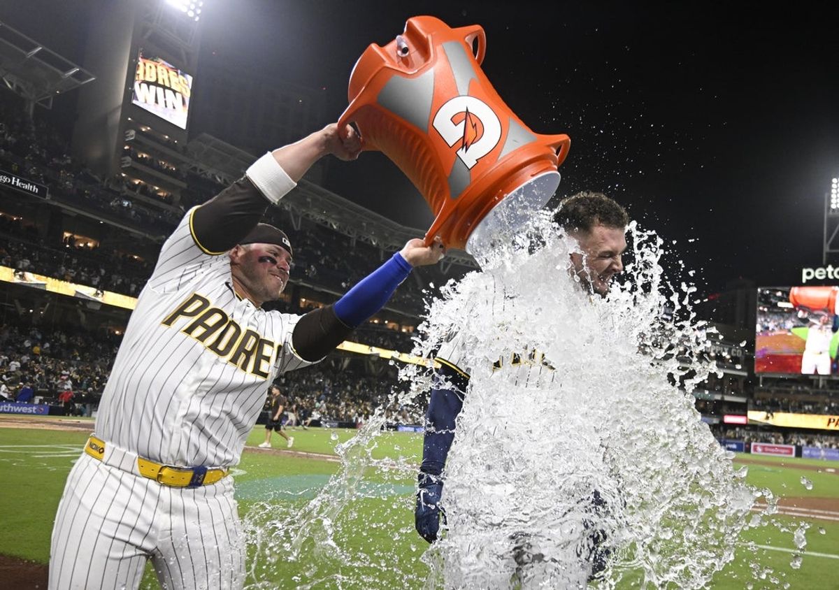 Apr 15, 2026; San Diego, California, USA; San Diego Padres first baseman Ty France, left, dumps a cooler over center fielder Jackson Merrill after he hit a walk-off double during the ninth inning against the Seattle Mariners at Petco Park. All MLB players are wearing number 42 today to honor Jackie Robinson. Mandatory Credit: Denis Poroy-Imagn Images