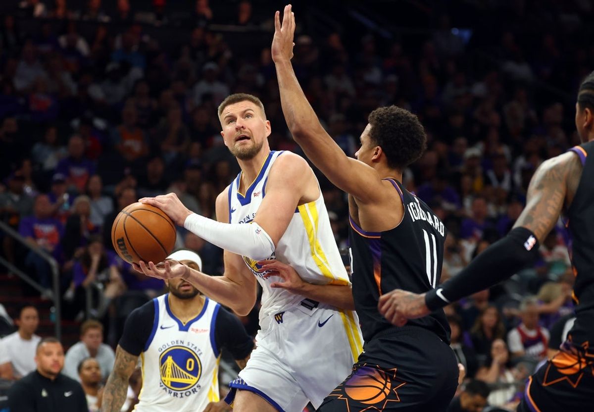 17 de abril de 2026; Phoenix, Arizona, EUA; O pivô do Golden State Warriors, Kristaps Porzingis (7), dirige para a cesta contra o atacante do Phoenix Suns, Oso Ighodaro (11), durante o segundo tempo nas rodadas de play-in dos Playoffs da NBA de 2026 no Mortgage Matchup Center. Crédito obrigatório: Mark J. Rebilas-Imagn Images