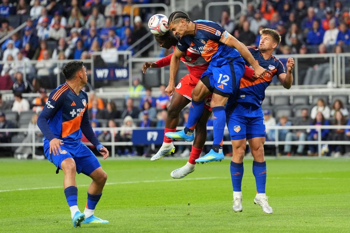 Apr 18, 2026; Cincinnati, Ohio, USA; FC Cincinnati defender Miles Robinson (12) (center) heads the ball clear away from Chicago Fire FC midfielder Dje D’avilla (42) during the first half of an MLS match at TQL Stadium. Mandatory Credit: Kareem Elgazzar-Imagn Images