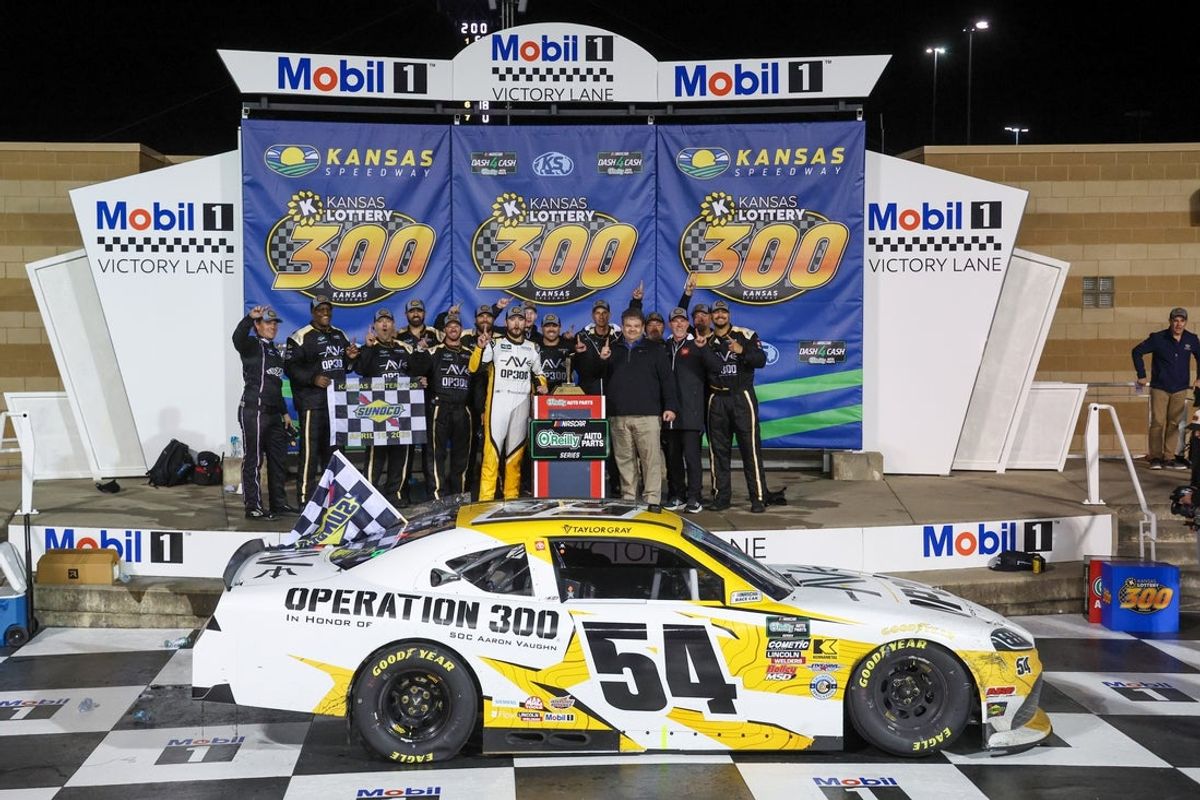 Apr 18, 2026; Kansas City, Kansas, USA; NASCAR O’Reilly Auto Parts Series driver Taylor Gray (54) poses with his team after winning the Kansas Lottery 300 at Kansas Speedway. Mandatory Credit: Scott Sewell-Imagn Images