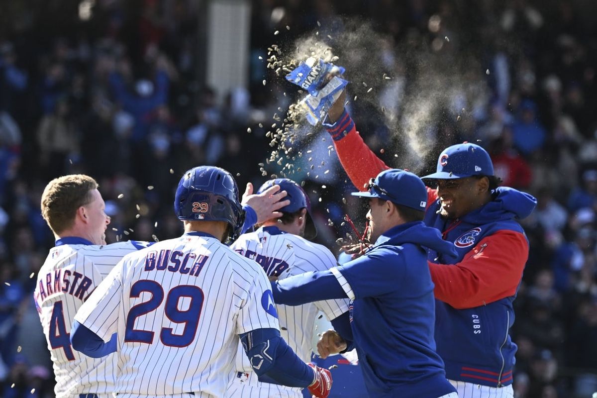 Apr 19, 2026; Chicago, Illinois, USA;  Chicago Cubs second baseman Nico Hoerner (2), center, is surrounded by teammates after he hits an RBI sacrifice fly ball during the tenth inning against the New York Mets at Wrigley Field. Mandatory Credit: Matt Marton-Imagn Images