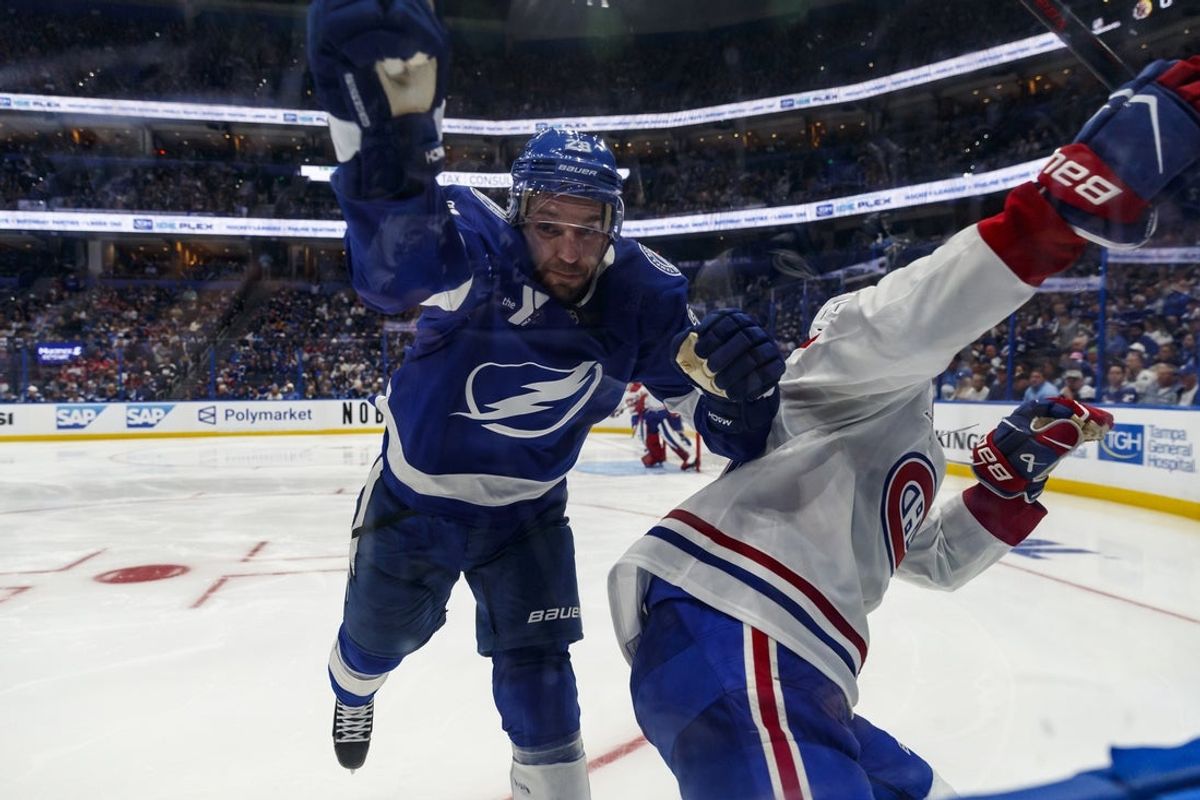Apr 19, 2026; Tampa, Florida, USA; Montreal Canadiens defenseman Kaiden Guhle (21) shoves Tampa Bay Lightning forward Zemgas Girgensons (28) into the boards during the third period in game one of the first round of the 2026 Stanley Cup Playoffs at Benchmark International Arena. Mandatory Credit: Morgan Tencza-Imagn Images