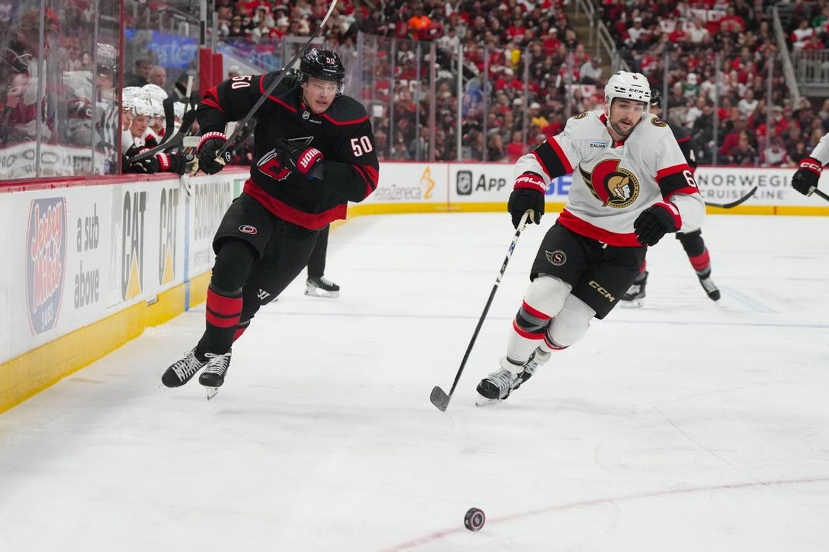 Apr 20, 2026; Raleigh, North Carolina, USA; Ottawa Senators defenseman Dennis Gilbert (6) and Carolina Hurricanes left wing Eric Robinson (50) chase after the puck during the first period in game two of the first round of the 2026 Stanley Cup Playoffs at Lenovo Center. Mandatory Credit: James Guillory-Imagn Images